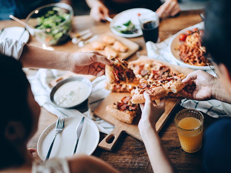 A group of people sitting around a table with various dishes of food