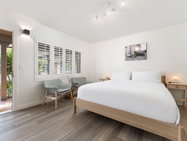 A wide view of a hotel room with a large bed, two chairs, and a window.